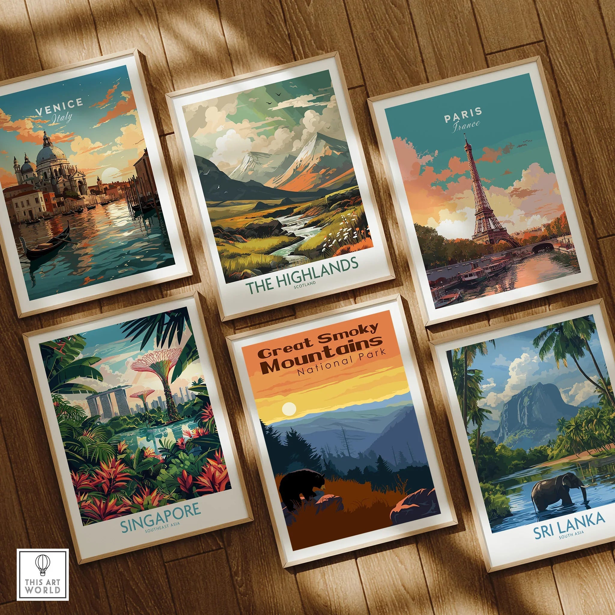 Set of six framed travel posters featuring Venice, Paris, the Highlands, Singapore, Great Smoky Mountains, and Sri Lanka, displayed on a wooden floor.