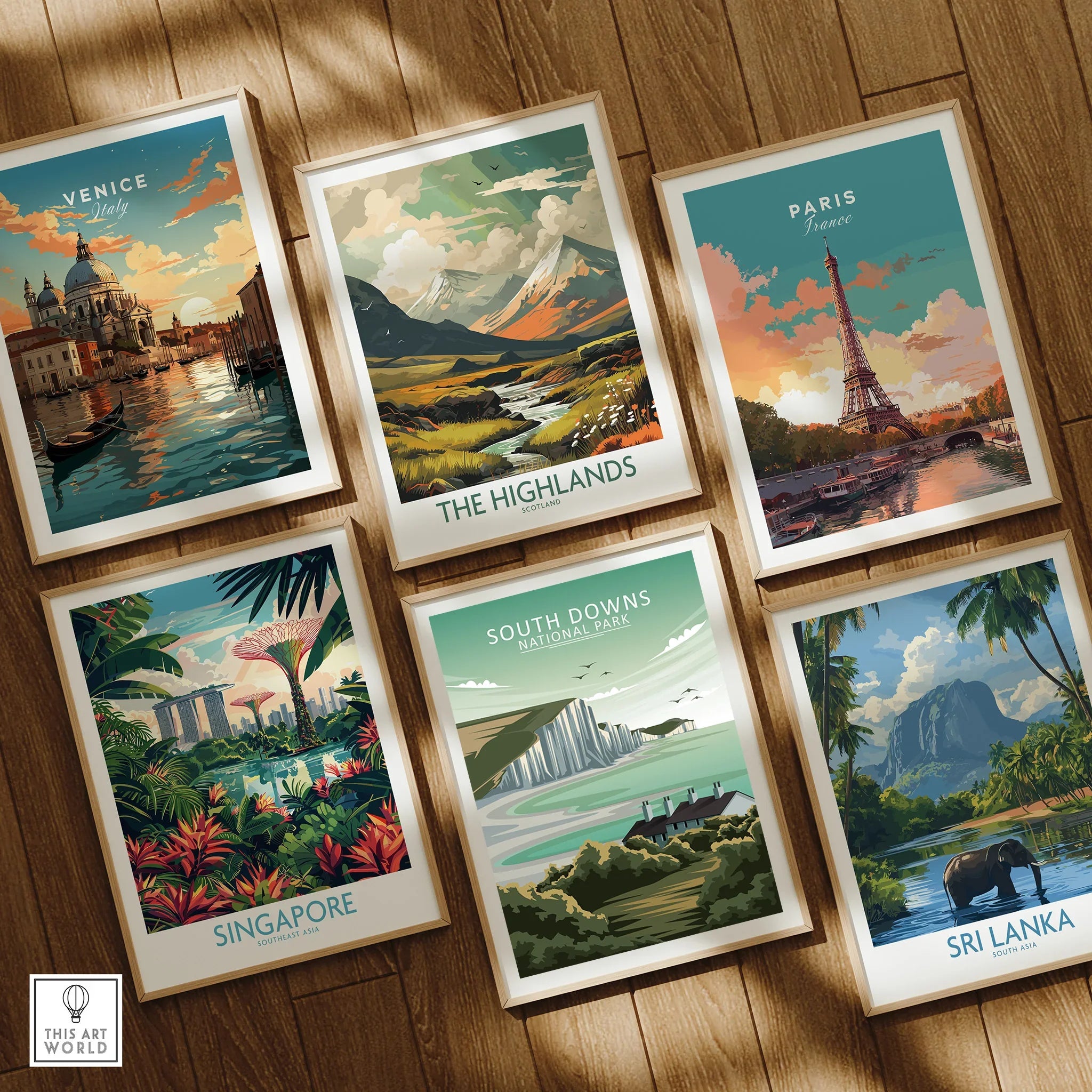 Set of six framed travel posters featuring Venice, Paris, Singapore, Sri Lanka, Scottish Highlands, and South Downs National Park on a wooden floor.