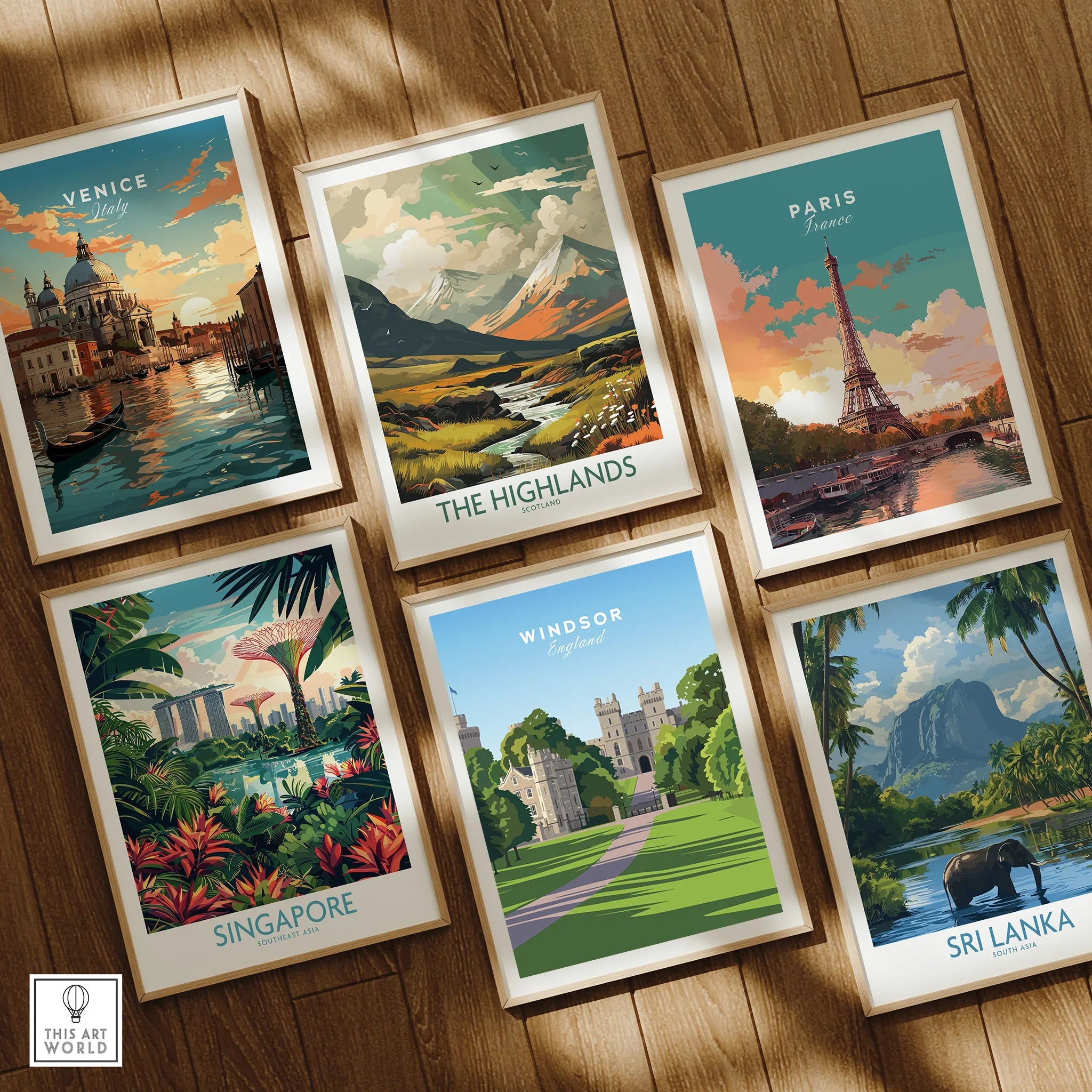 Six framed travel and nature art prints on wooden floor, featuring Venice, Paris, Highlands, Singapore, Windsor, and Sri Lanka.