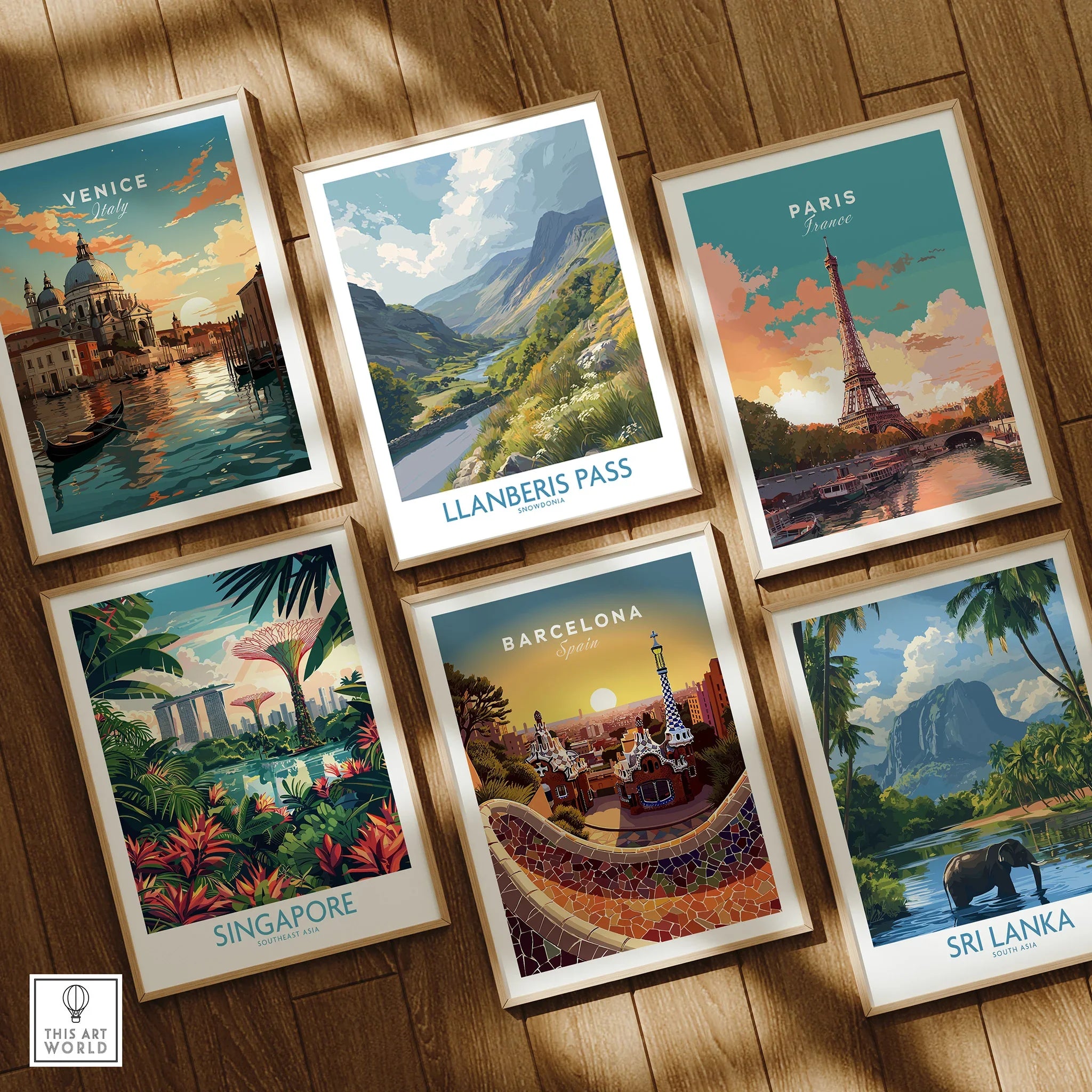 Set of six framed travel posters featuring Venice, Paris, Llanberis Pass, Singapore, Barcelona, Sri Lanka, displayed on wooden floor.