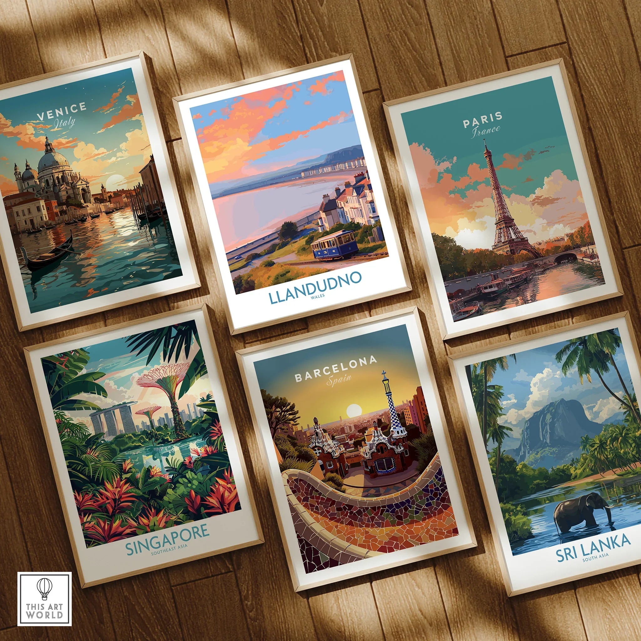 Set of six framed travel art prints featuring Venice, Llandudno, Paris, Singapore, Barcelona, Sri Lanka on wooden floor