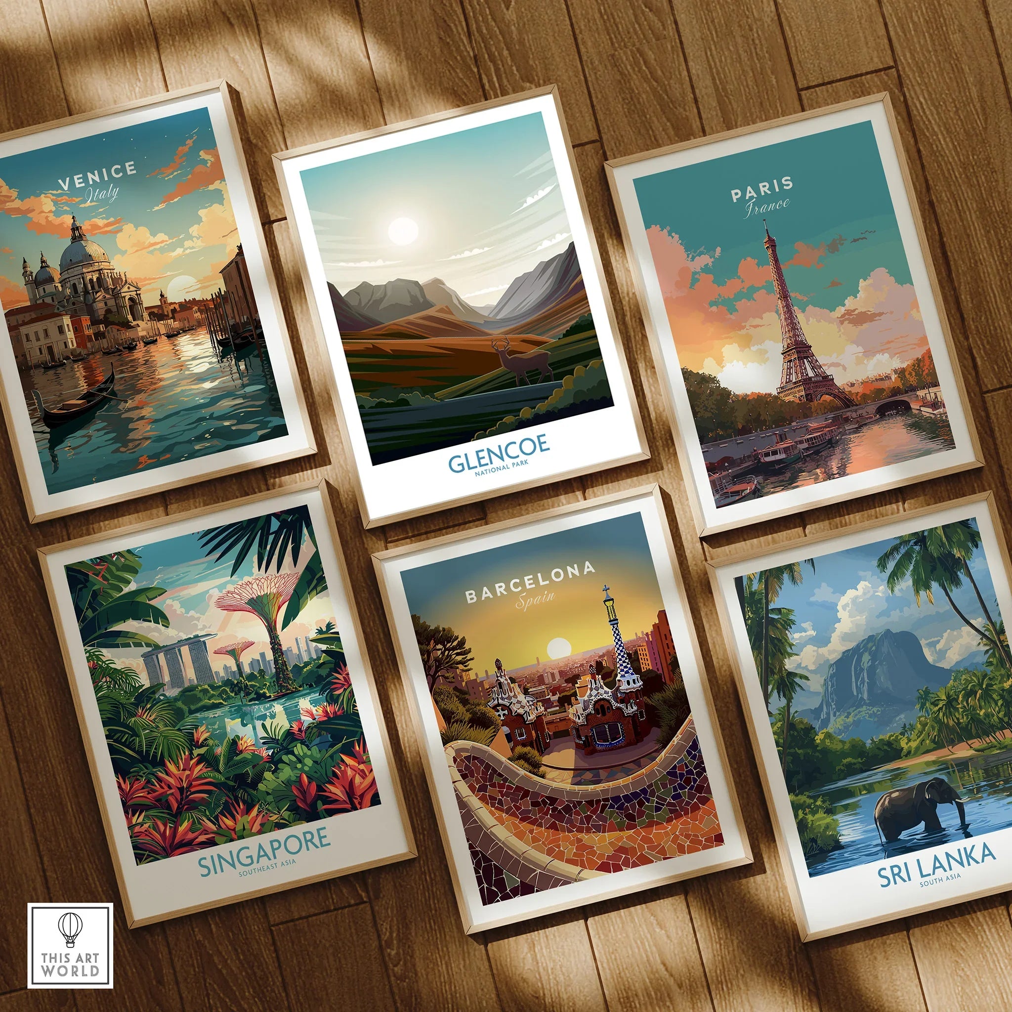 Set of six framed travel art prints on wooden floor featuring Venice, Paris, Barcelona, Singapore, Sri Lanka, and Glencoe National Park.