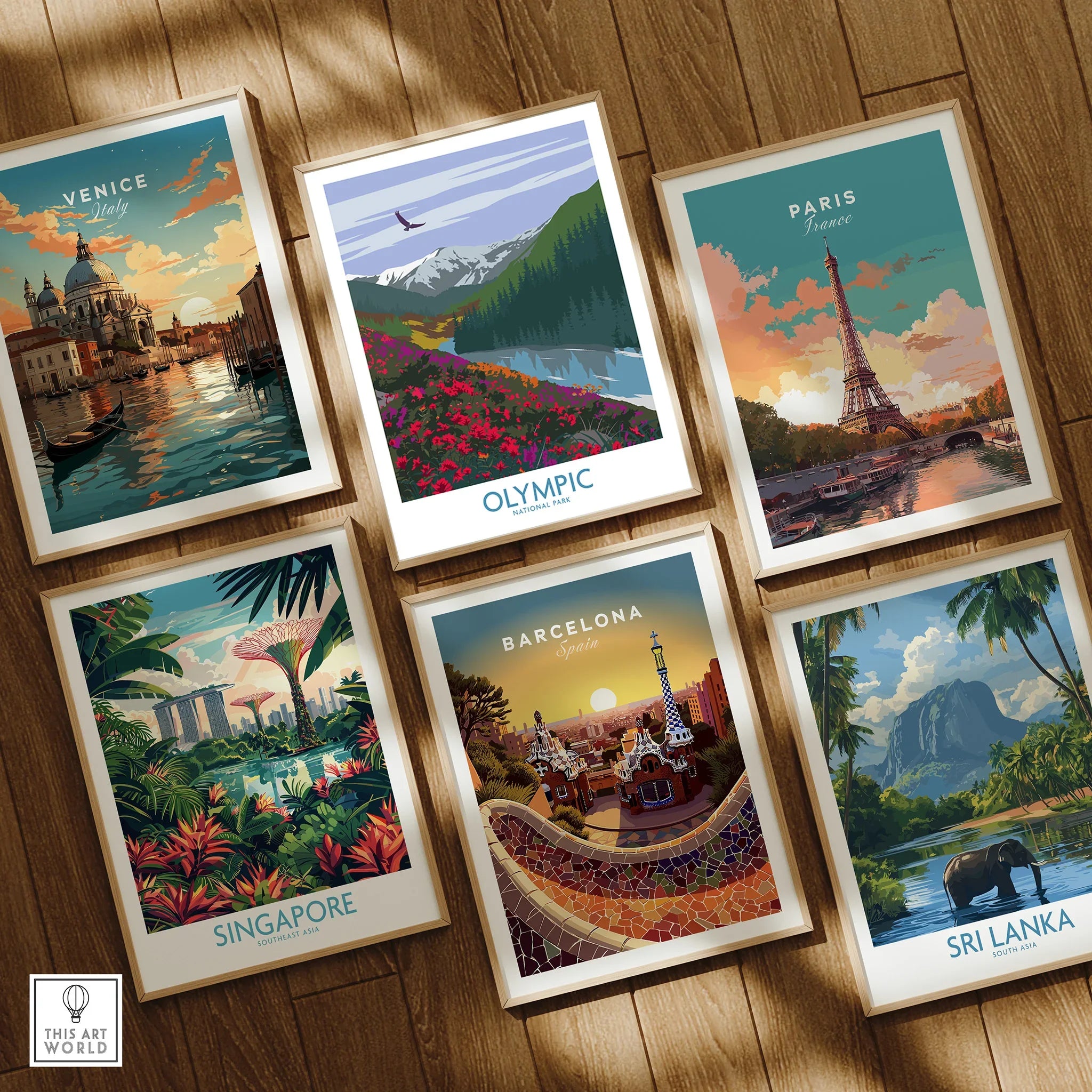 Set of six framed travel posters featuring Venice, Olympic National Park, Paris, Singapore, Barcelona, and Sri Lanka on a wooden floor.