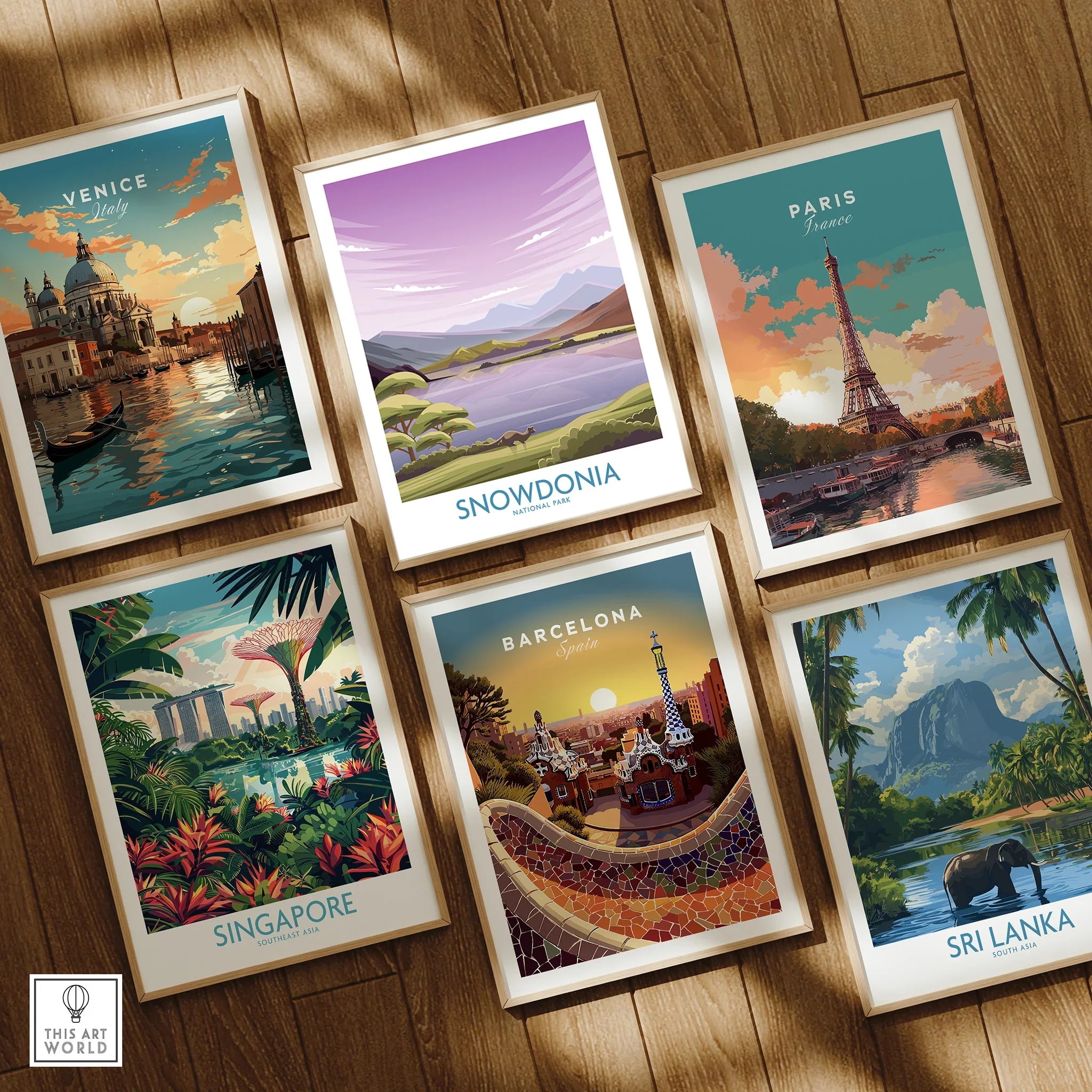 Set of six framed travel posters art prints on wooden floor, including Venice, Paris, Snowdonia, Singapore, Barcelona, Sri Lanka.