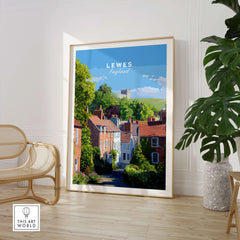 Framed Lewes England travel poster with colorful houses, displayed in a modern room with a chair and plant.