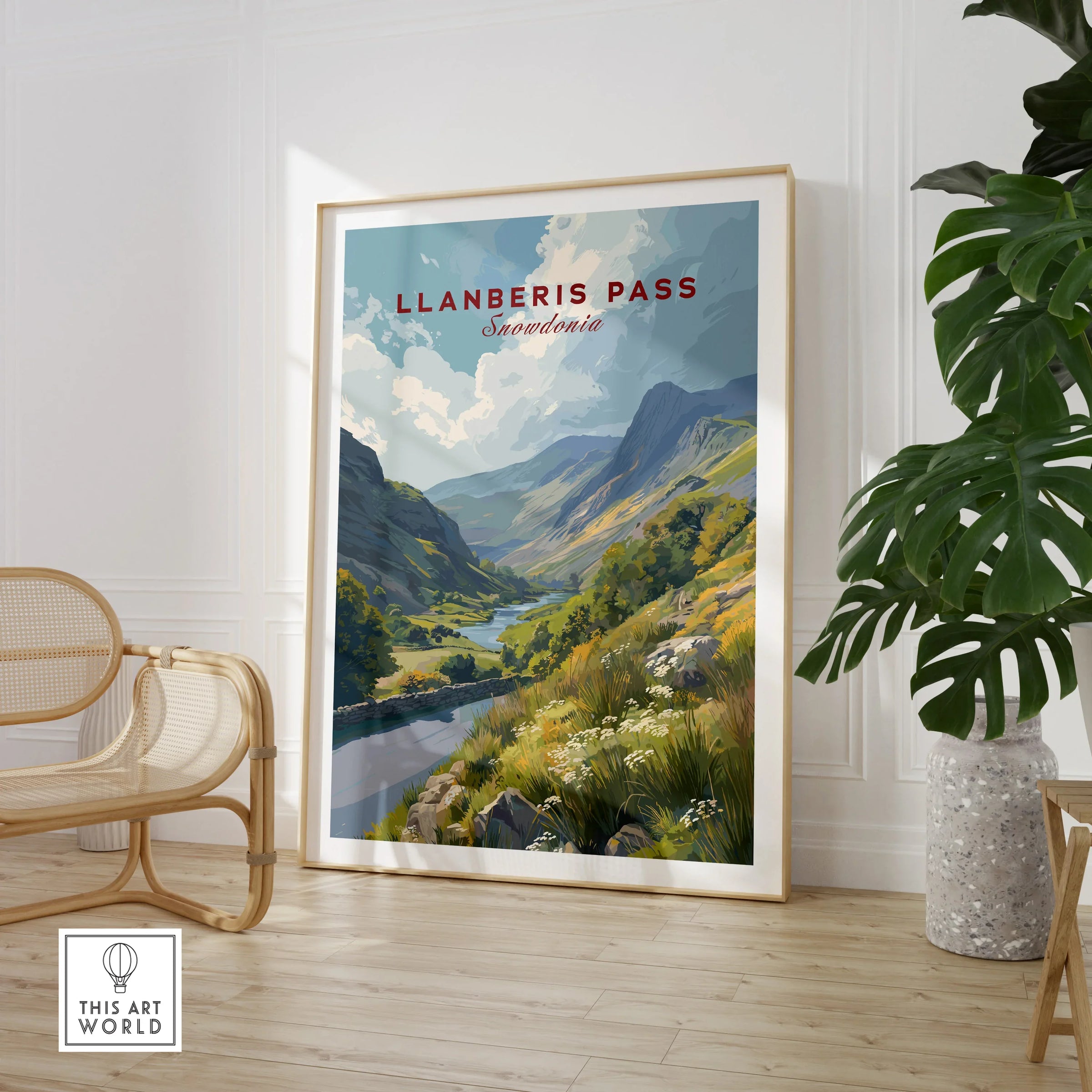 Framed Llanberis Pass Snowdonia travel print in modern room with chair and houseplant