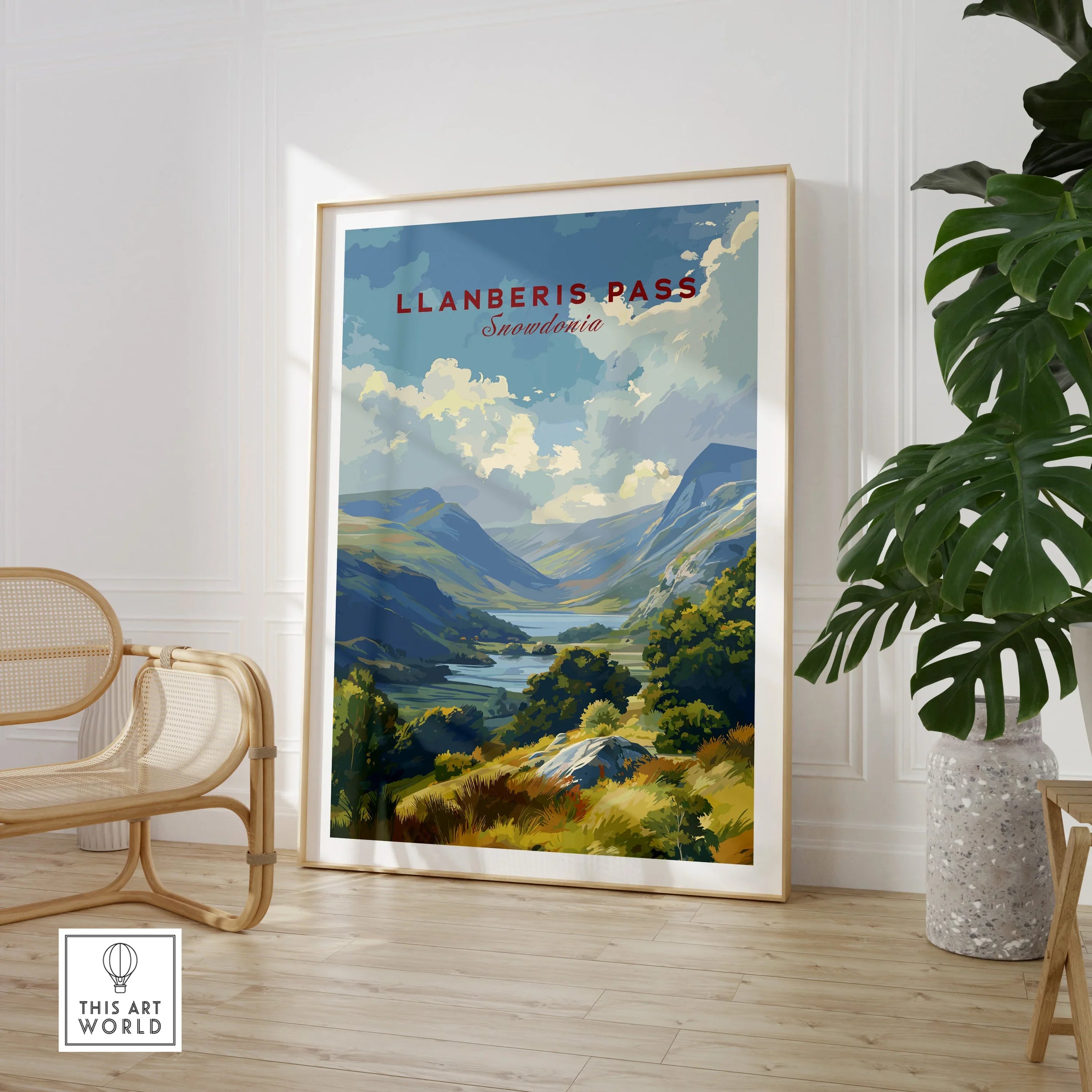 Llanberis Pass Snowdonia travel poster framed, displayed in modern room with chair and plant.