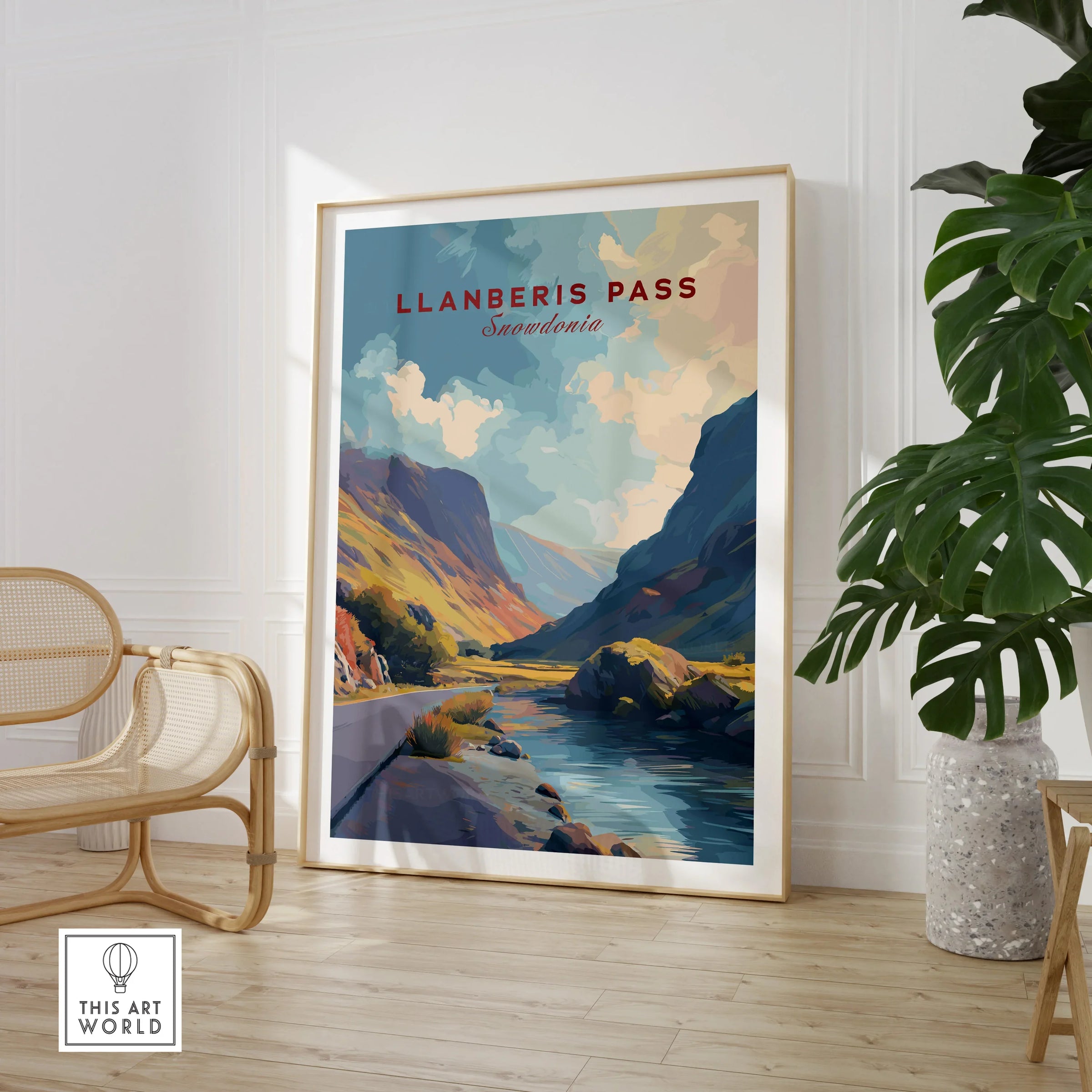 Framed Llanberis Pass Snowdonia travel art print in modern living room with chair and plant.