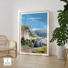 Framed Llandudno Wales travel poster with tram, displayed in modern living room with chair and plant