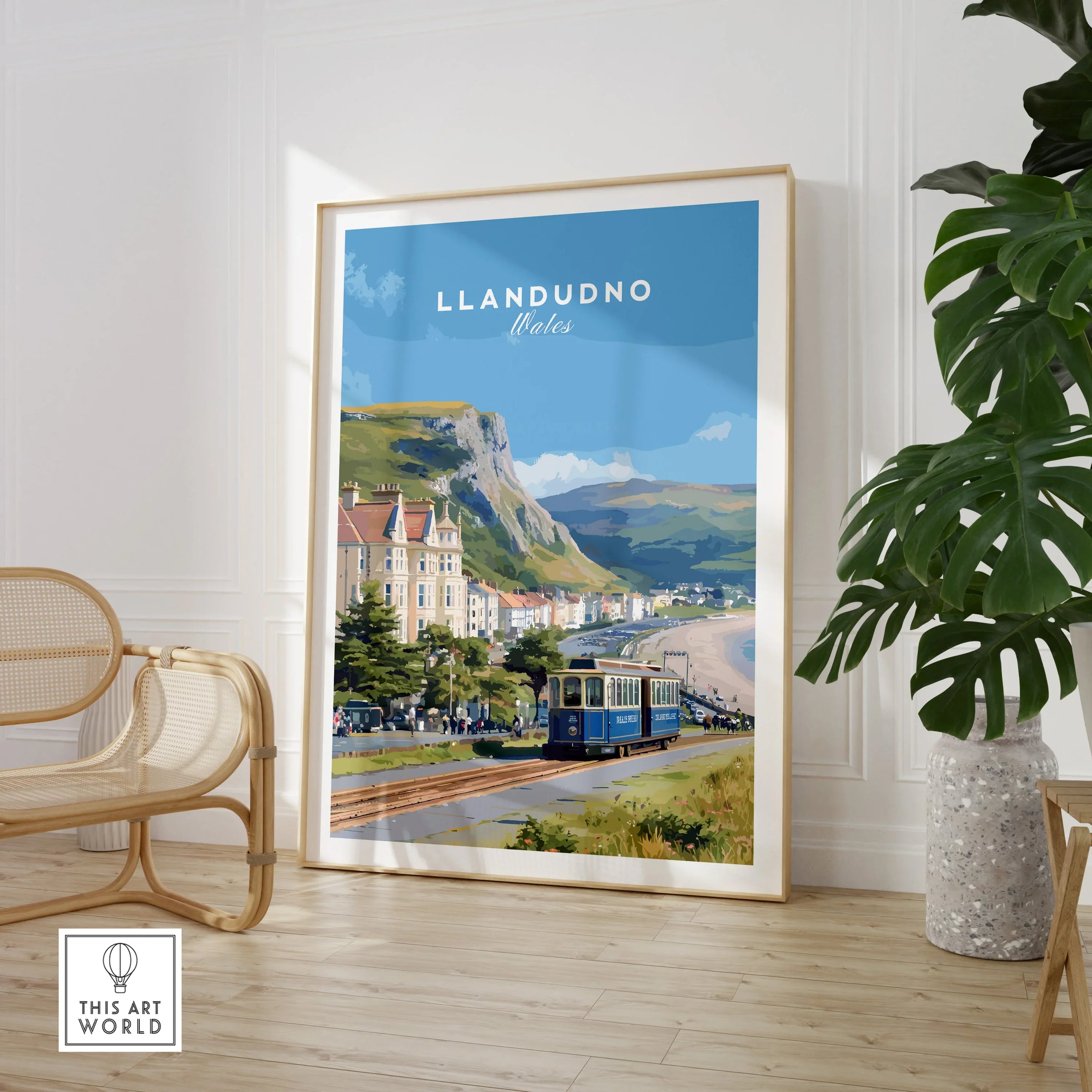 Framed Llandudno Wales travel poster with tram, displayed in modern living room with chair and plant