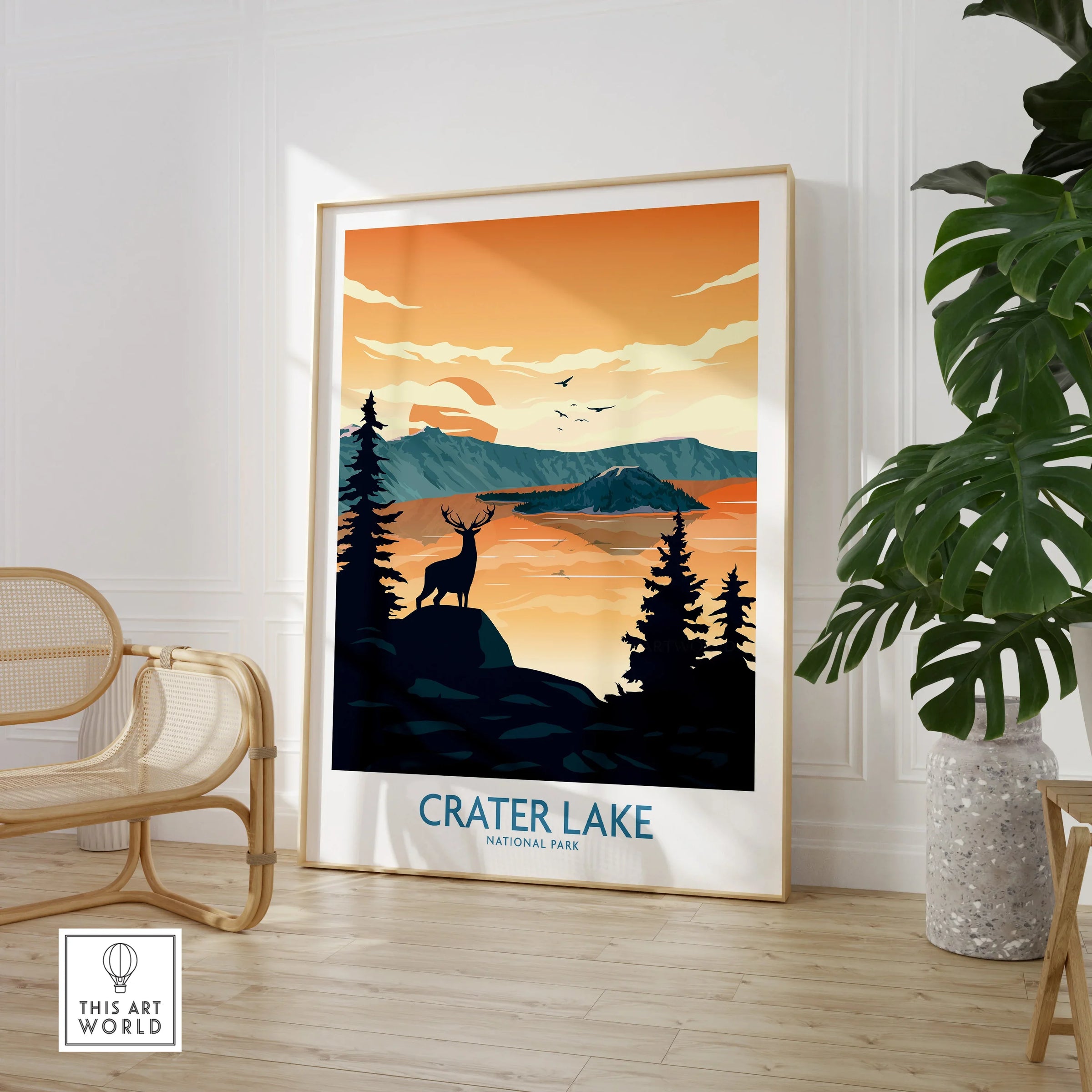 Framed Crater Lake National Park art print with deer and sunset in modern room with chair and plant