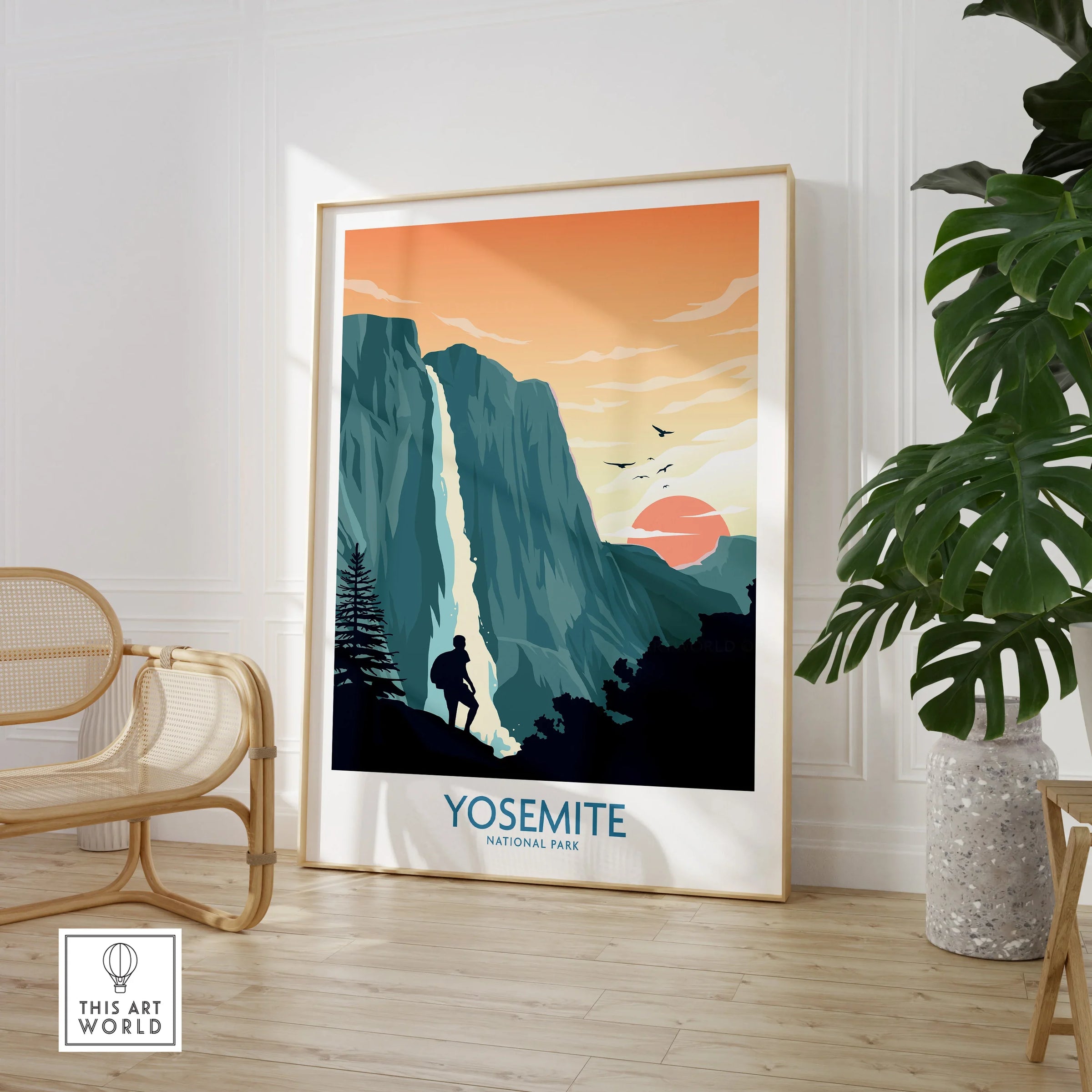 Framed Yosemite National Park travel poster with waterfall and hiker in a modern room with chair and plant.