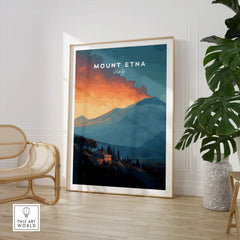 Framed Mount Etna travel poster with vibrant sunset, displayed in modern living room with chair and plant.
