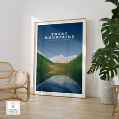 Framed Rocky Mountains National Park travel poster in modern room with chair and plant