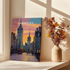 Aberdeen Scotland travel poster wall art with city skyline, red bus, and sunset, styled on windowsill with dried flowers.