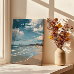 Aberdeen Scotland travel poster print with beach, lighthouse, and clouds, styled on a sunny windowsill with dried flowers.