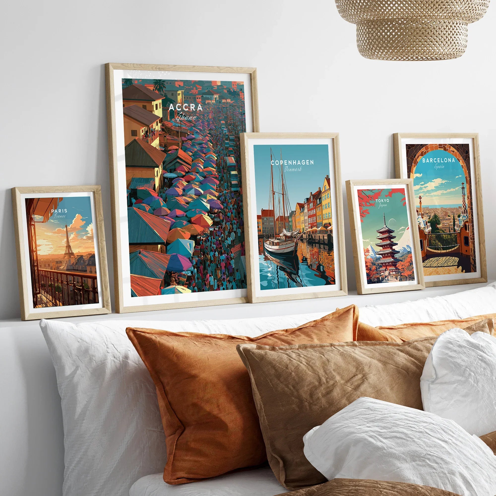 Set of five framed travel art prints including Accra Ghana above a bed in natural wood frames