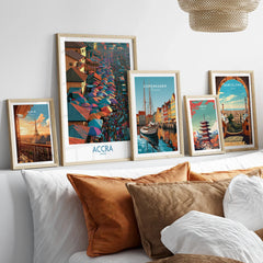 Set of five framed travel art prints including Accra Ghana above a bed in natural wood frames
