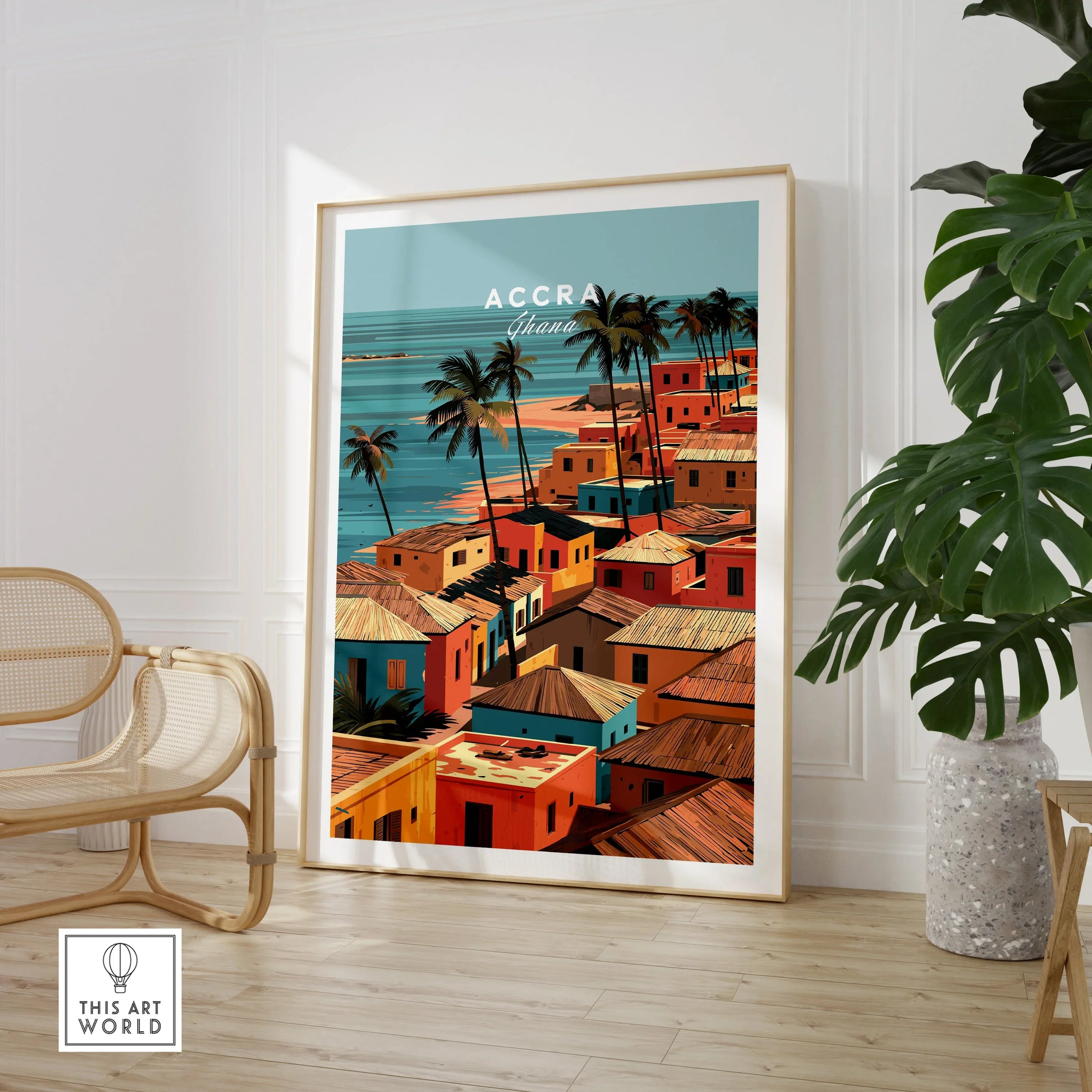 Large framed Accra Ghana coastal village print in a room with chair and plant