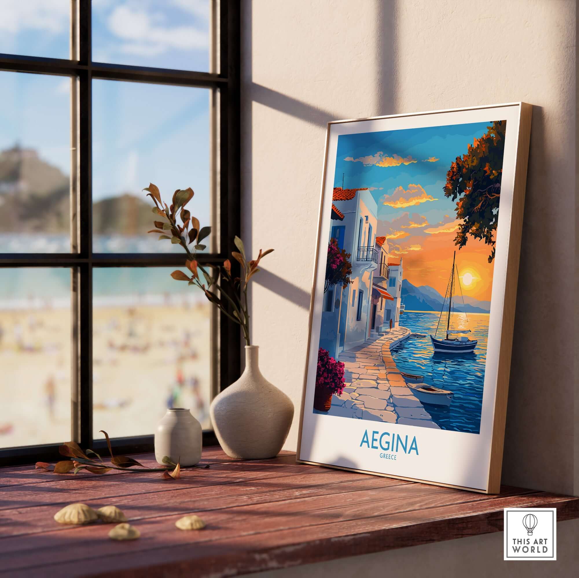 Aegina Travel Poster displayed on a wooden table next to vases, with a beach view in the background.