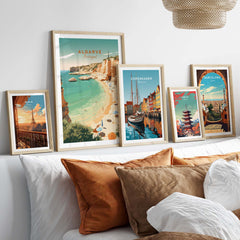 Algarve Beach poster displayed among vintage travel prints on a cozy bed with decorative pillows.