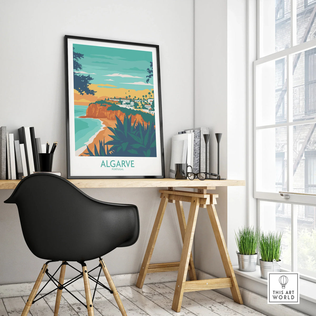 Algarve Portugal travel poster print with coastal cliffs, beach, and town, displayed on a modern desk.