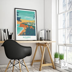Algarve Portugal travel poster print with coastal cliffs, beach, and town, displayed on a modern desk.