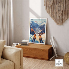 Alpe d'Huez Ski Print framed on a wooden table in a cozy living room, showcasing the beauty of the French Alps.