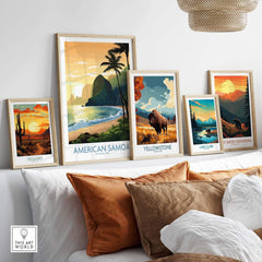 Framed travel posters of national parks including American Samoa, Yellowstone, and Great Smoky Mountains on a white wall above a cozy sofa with pillows.