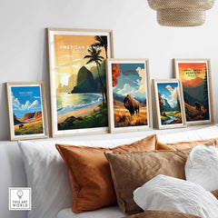 Framed travel posters of American Samoa, Yellowstone, Yosemite, Badlands, and Great Smoky Mountains National Parks displayed above a modern sofa with brown and white pillows.