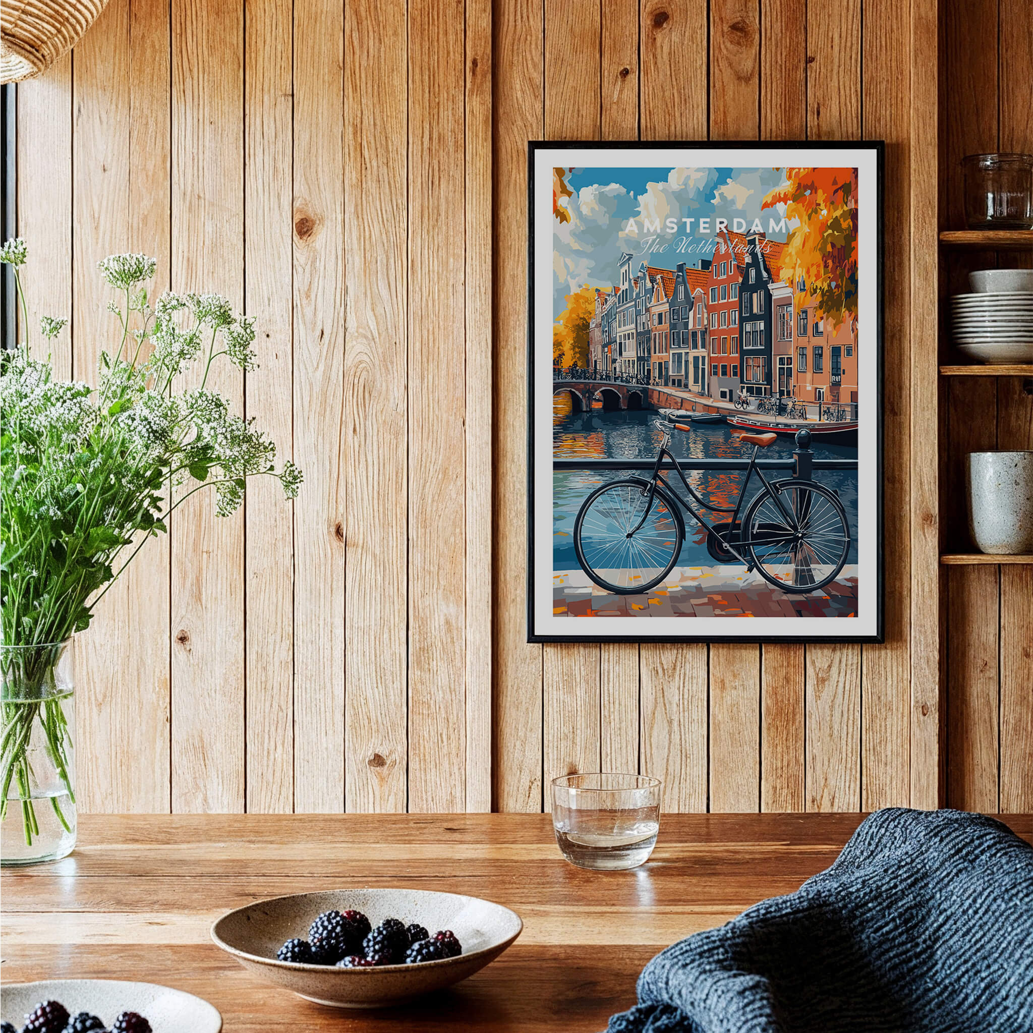 Colorful Amsterdam Canal House Poster - Classic Dutch Canal Scene Print displayed on a wooden wall with flowers and table.