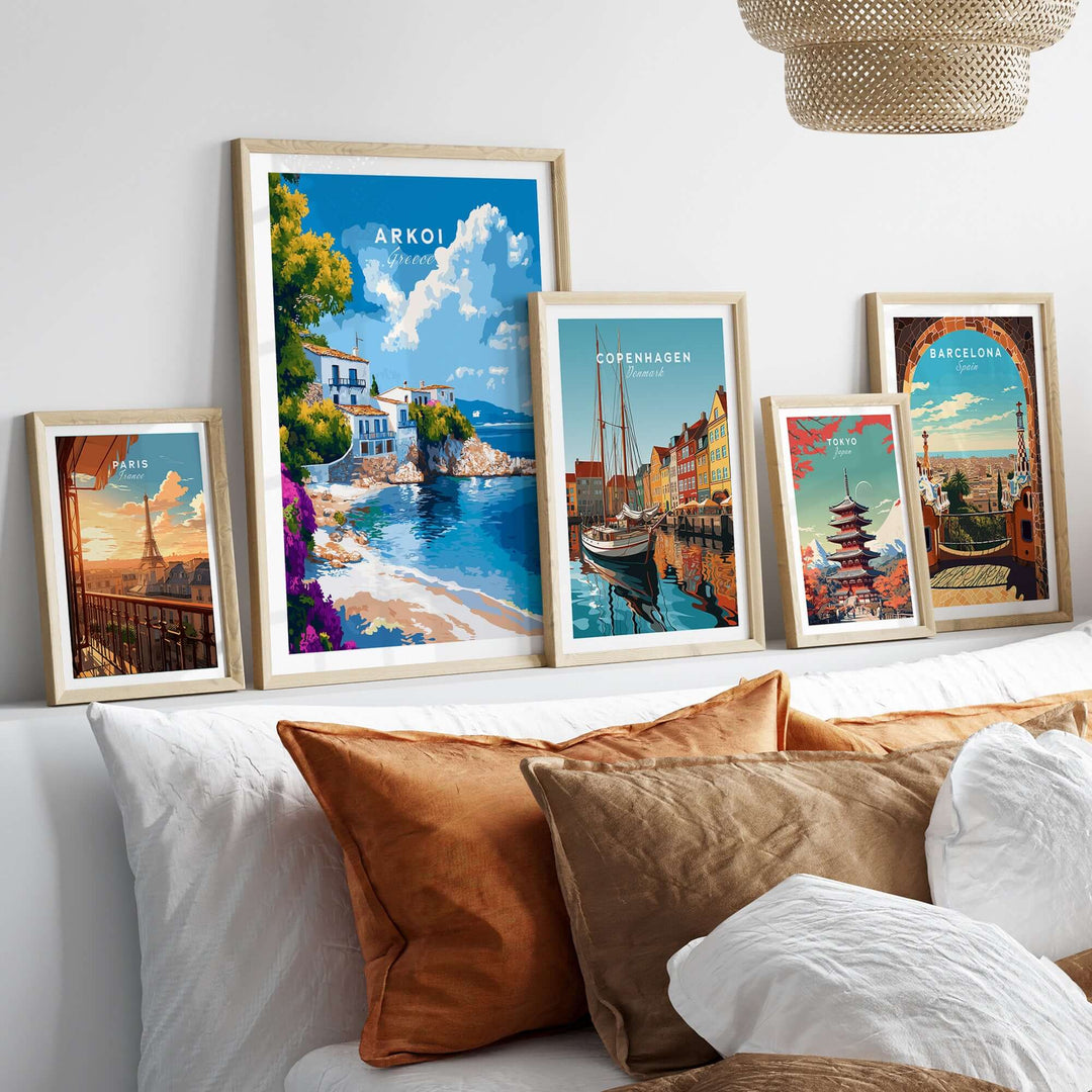 Arkoi Greece wall art displayed on a bed, showcasing vibrant Mediterranean landscapes and cityscapes in framed prints.