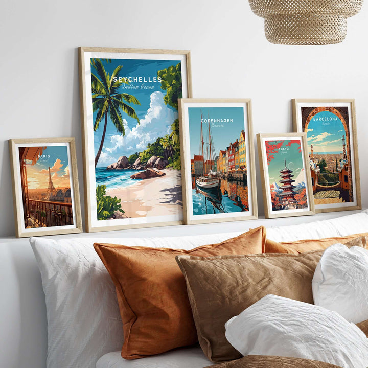 Collection of framed travel posters including Seychelles, Copenhagen, and Barcelona on a modern bed.