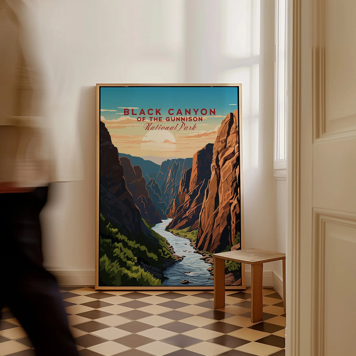 Framed Black Canyon National Park travel poster on floor, man walking past in modern home.