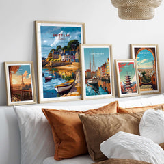 Brittany Travel Print and other vibrant travel prints displayed on a cozy wall above a stylish sofa.