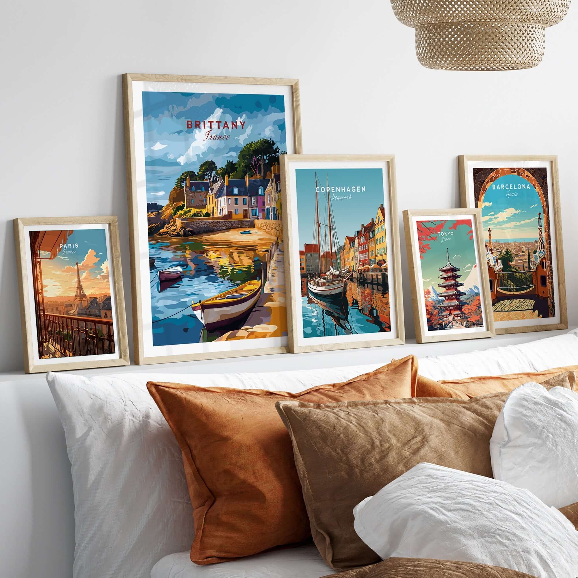 Brittany Travel Print and other vibrant travel prints displayed on a cozy wall above a stylish sofa.