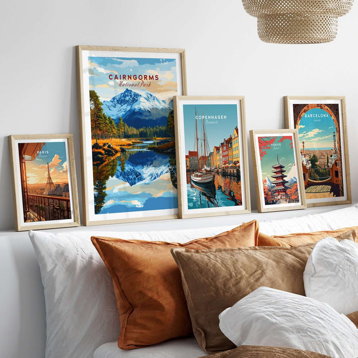 Framed prints of Cairngorms National Park and other cities displayed on a stylish bed with decorative pillows.