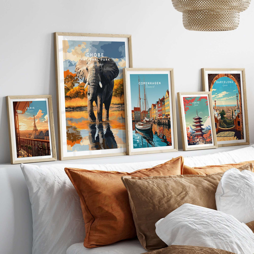 Chobe National Park elephant poster and travel art prints on a wall above a cozy bed with decorative pillows.