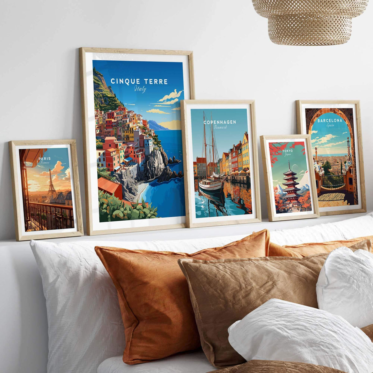 Cinque Terre Travel Poster displayed among travel posters on a cozy bed with decorative pillows.
