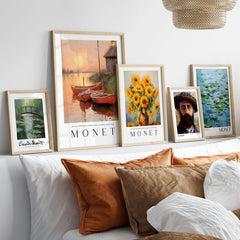 Claude Monet Art Print - Red Boats at Sunset Riverbank Wall Art framed alongside other Monet works on a cozy interior shelf.