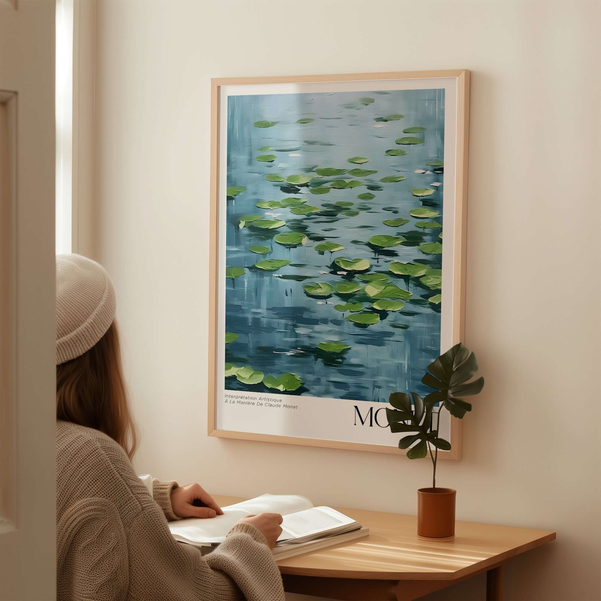 Claude Monet Print - Calm Lily Pads on Blue Water Wall Art displayed above a wooden desk with a person reading.