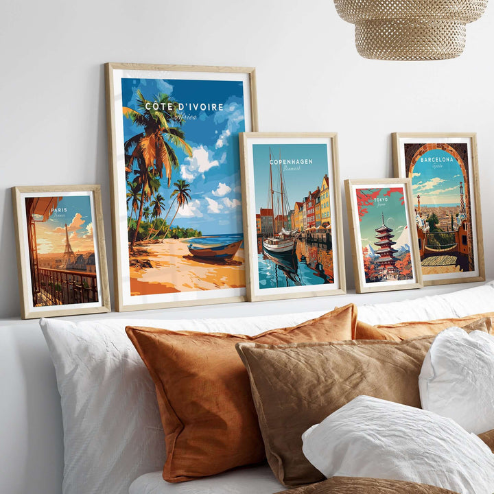 Côte d'Ivoire poster and travel art prints displayed above a bed with decorative pillows.