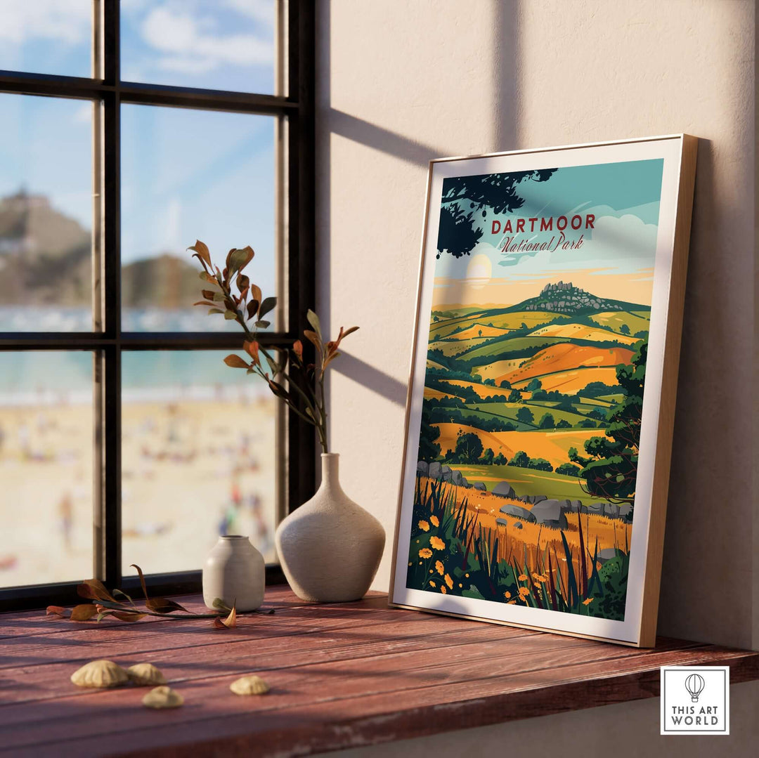 Framed Dartmoor National Park wall art displayed indoors with natural light and a view of sandy beach outside.