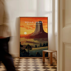 Framed Devils Tower National Monument travel poster on floor, man walking by, checkered tile floor