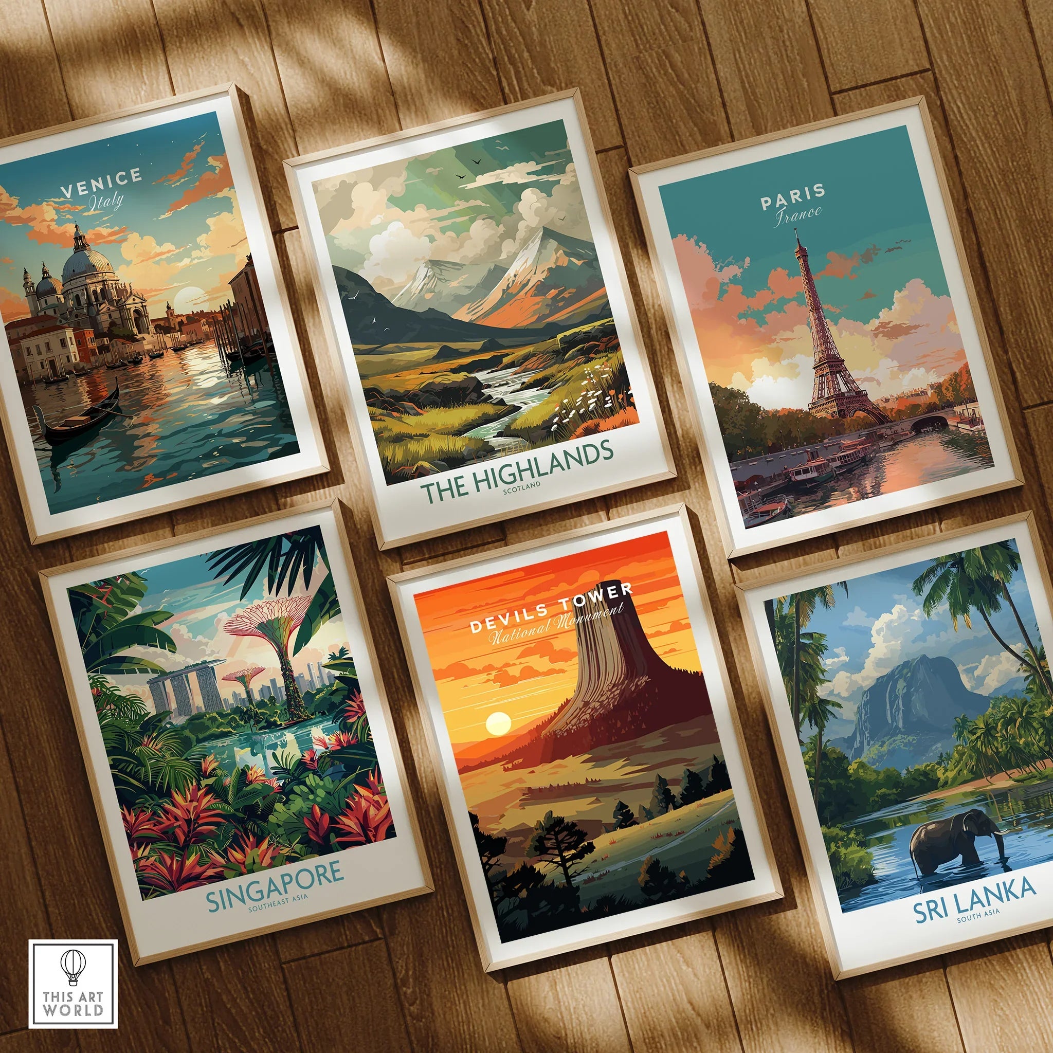 Set of six framed travel posters with colorful illustrations of Venice, Paris, The Highlands, Singapore, Devils Tower, and Sri Lanka on a wooden floor.