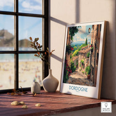 Dordogne Travel Poster featuring a picturesque street scene in Dordogne, France, framed and displayed on a wooden windowsill.