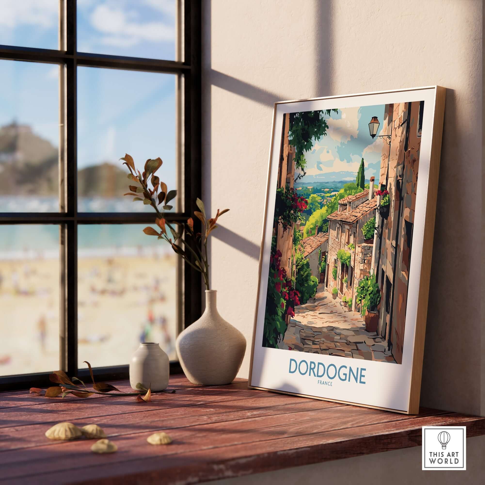 Dordogne Travel Poster featuring a picturesque street scene in Dordogne, France, framed and displayed on a wooden windowsill.
