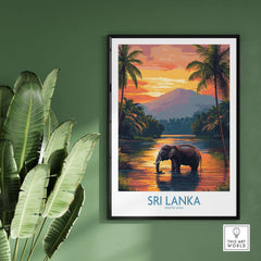 Elephant River Scene Print - Sri Lanka Travel Art, Tropical Wall Hanging displayed on a wall with tropical plants nearby.