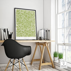 Framed green botanical art print on modern office desk with black chair and natural light