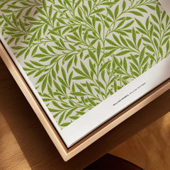 Closeup of framed canvas wall art with green willow leaf pattern in natural wood frame